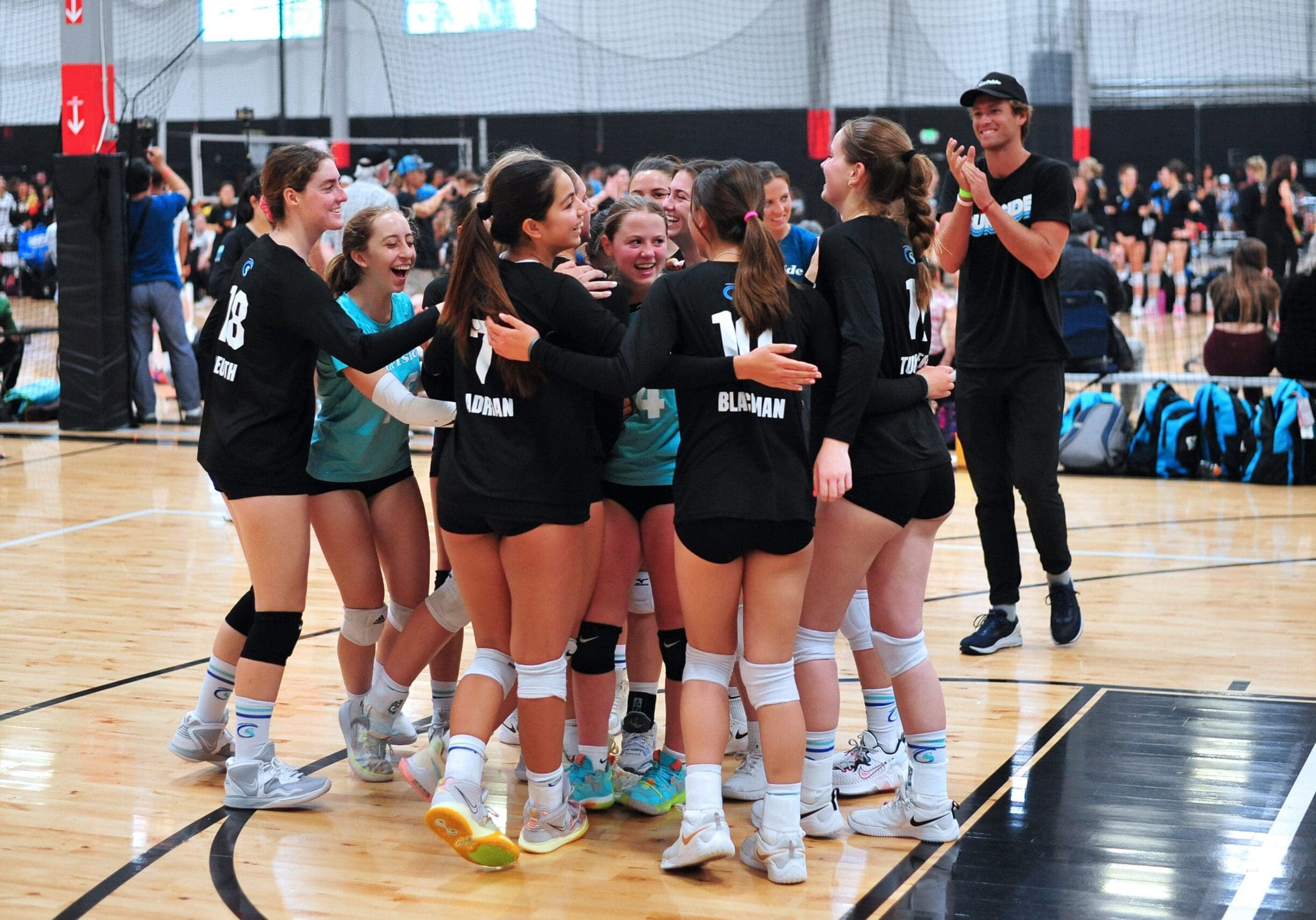 Girls volleyball team in a huddle celebrating